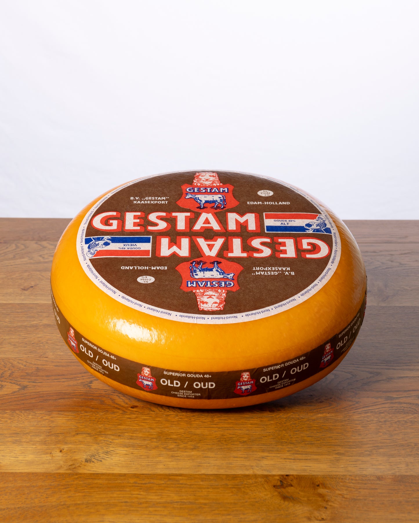 Een hele wielvormige Goudse 48+ Oud op een houten tafel.