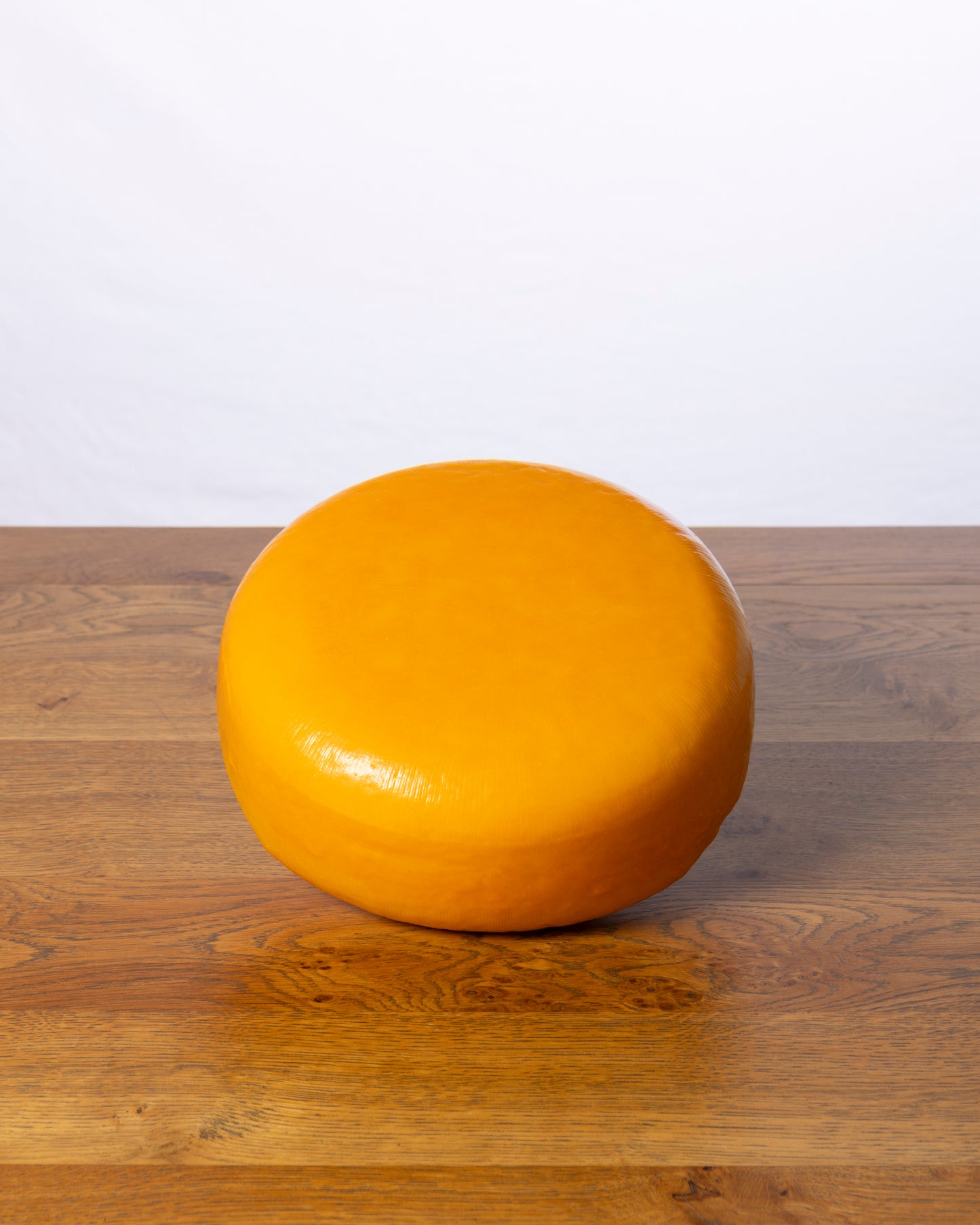 Een hele wielvormige Goudse 50+ Jong Belegen op een houten tafel.