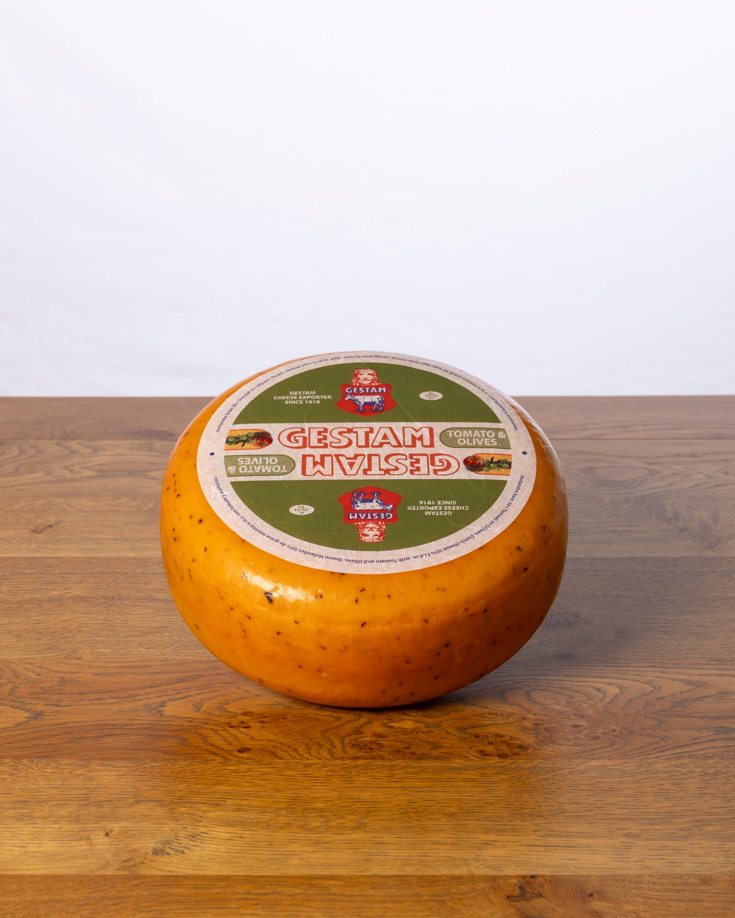 Een hele wielvormige Tomaat/Olijf 50+ Jong kaas op een houten tafel.